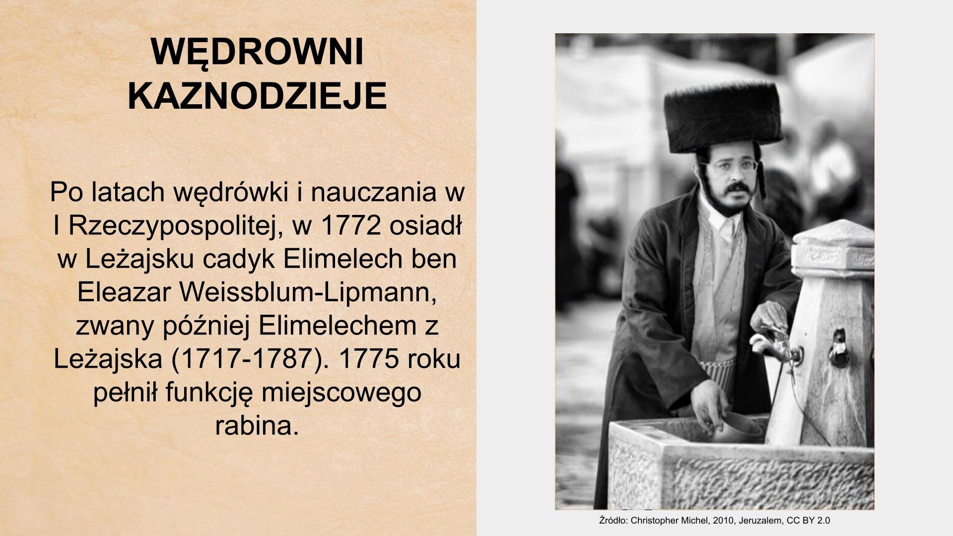 W lewym górnym rogu slajdu tytuł: „Wędrowni kaznodzieje”. Poniżej tekst: „Po latach wędrówki i nauczania w I Rzeczypospolitej, w 1772 osiadł w Leżajsku cadyk Elimelech ben Eleazar Weissblum‑Lipmann, zwany później Elimelechem z Leżajska (1717–1787). 1775 roku pełnił funkcję miejscowego rabina”. Po prawej stronie slajdu czarno‑białe zdjęcie przedstawiające młodego mężczyznę. Nosi dużą czapkę z szerokim otokiem, okulary, brodę i wąsy. Ubrany jest w koszulę i płaszcz. Nachyla się nad fontanną. Jedną ręką naciska kurek z wodą, w drugiej trzyma naczynie, do którego spływa woda. Pod zdjęciem podpis: „Źródło: Christopher Michel, 2010, Jeruzalem, CC BY 2.0”.