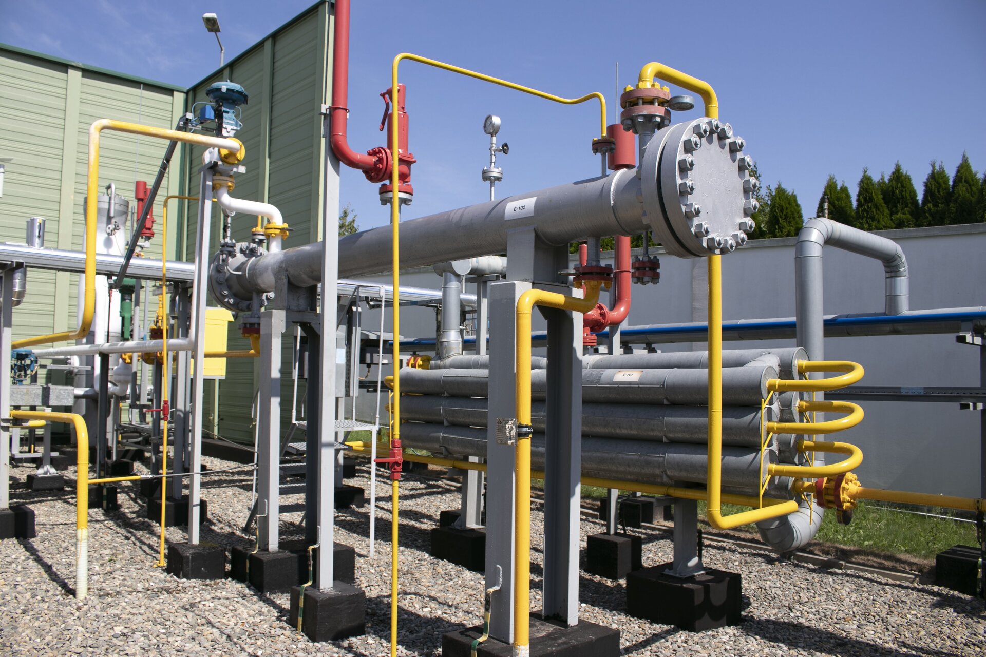 Na ekranie widoczny jest wymiennik ciepła. Wymiennik ciepła jest urządzeniem umożliwiającym wymianę ciepła pomiędzy płynami o różnej temperaturze. Wymiana ciepła zachodzi poprzez zjawiska konwekcji i przewodzenia.Widoczny na zdjęciu wymiennik składa się z długiego cylindra w orientacji poziomej pogrubionego na obu końcach. Znajduje się on na dwóch podstawach. Za wymiennikiem znajduje się siedem cylindrów w orientacji poziomej połączonych ze sobą za pomocą żółtych rur. Do wymiennika ciepła poprowadzona jest żółta rura wychodząca z ziemi. Nad wymiennikiem ciepła znajduje się ciśnieniomierz. Z lewej strony i w oddali znajduje się sieć rur różnego przeznaczenia.