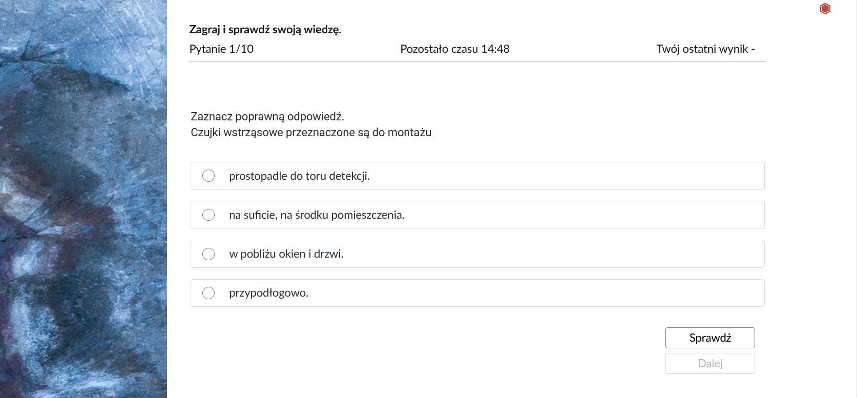 Grafika przedstawia przykładowe zadanie testowe. Ponad poleceniem widać numer pytania, czas, który pozostał na wypełnianie testu, oraz ostatni uzyskany wynik. Pod poleceniem znajdują się możliwe odpowiedzi. W prawym dolnym rogu panelu z zadaniem znajdują się dwa przyciski. Są to "Sprawdź" oraz "Dalej".
