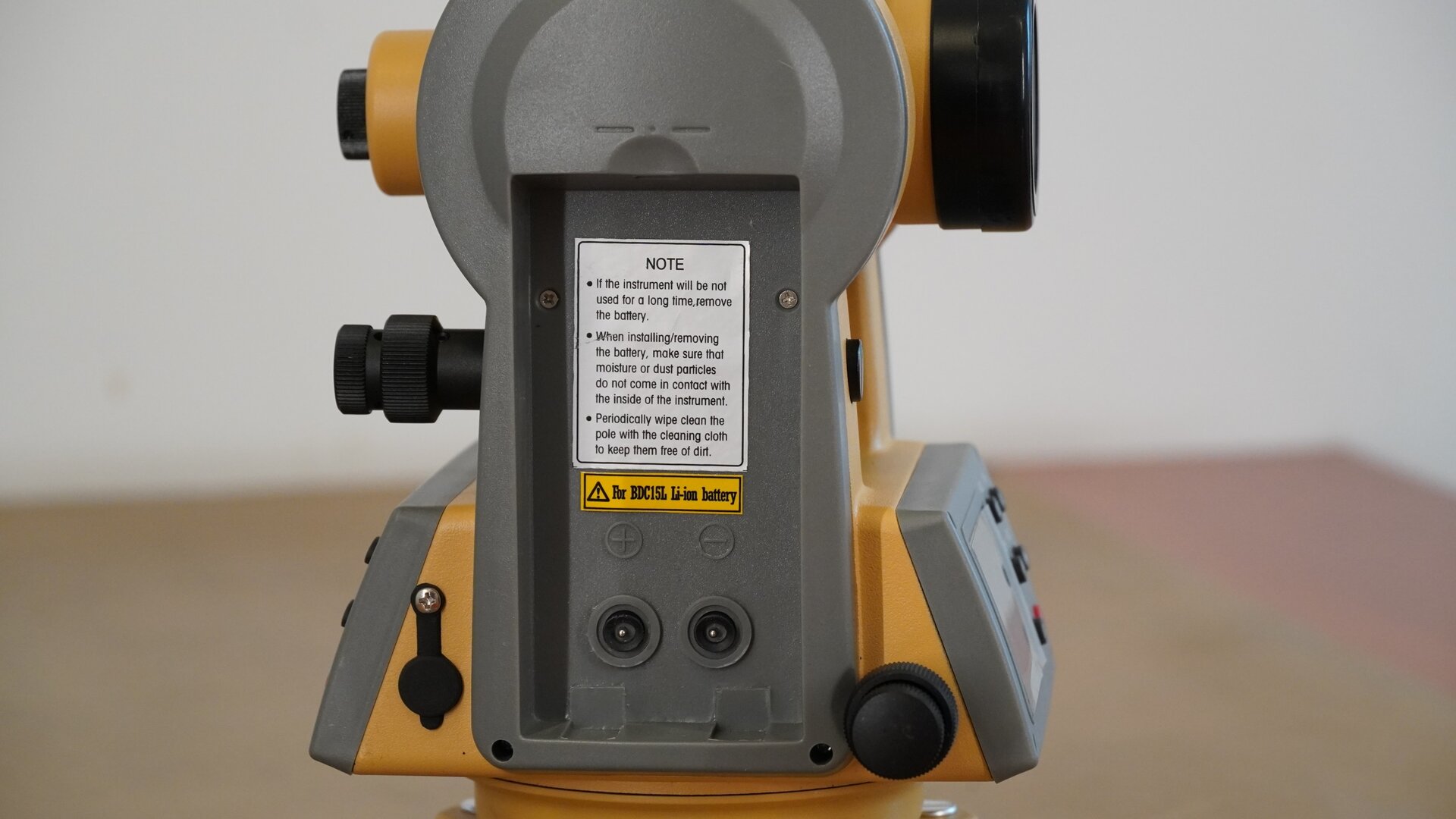 Zdjęcie przedstawia widok teodolitu z bocznej perspektywy. W bocznej części ramy obudowy znajduje się miejsce na baterie zasilające. Zdjęto z niego osłonę.