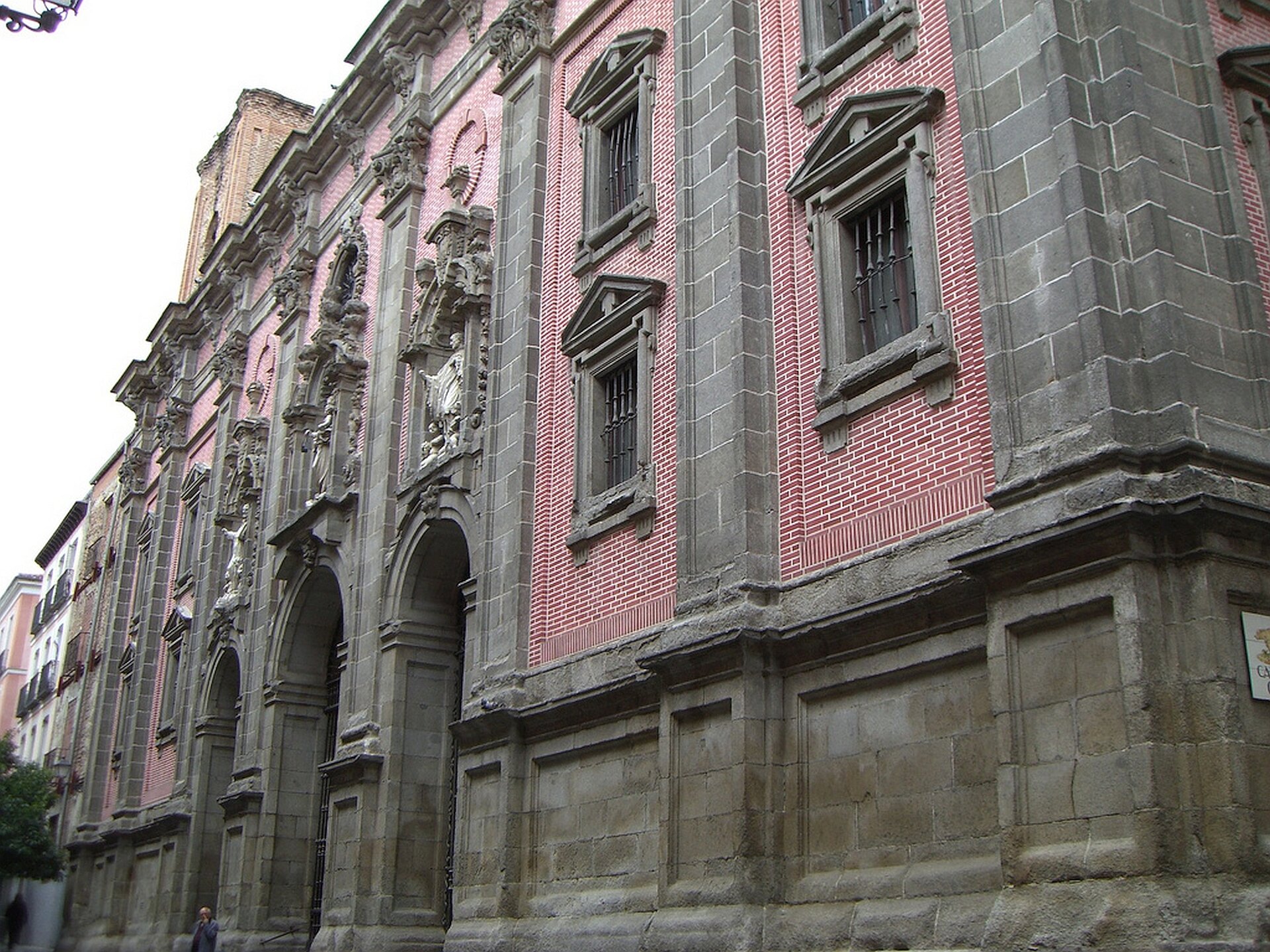 lustracja przedstawia kościół San Isidoro del Real w Madrycie. Na fotografii znajduje się monumentalna fasada. Dwuwieżowa, granitowa fasada dekorowana jest symetrycznie usytuowanymi kolumnami oraz pilastrami w stylu korynckim, zamieszczonymi na wysokich cokołach., Fasada jest flankowana wieżami na planie kwadratu; pomiędzy nimi znajduje się balustrada oraz kopuła, która wznosi się nad transeptem. Nad wejściem głównym zostały zamieszczone we wnęce rzeźby przedstawiające Izydora wraz z małżonką.