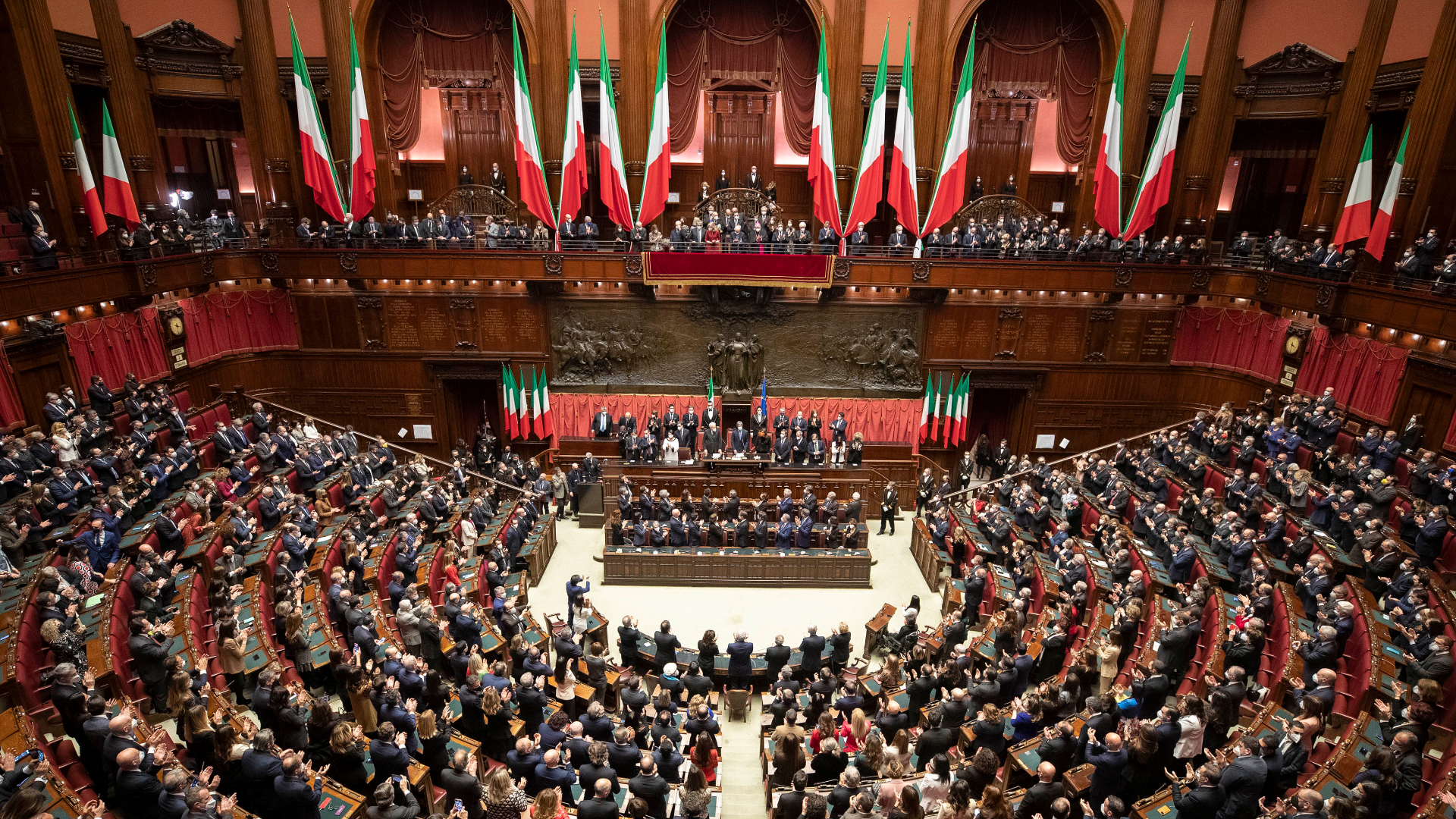 Zdjęcie przedstawia Izbę Deputowanych, odpowiednik polskiego Sejmu. Na zdjęciu deputowani zasiadają w ławach. Widoczne są włoskie flagi.