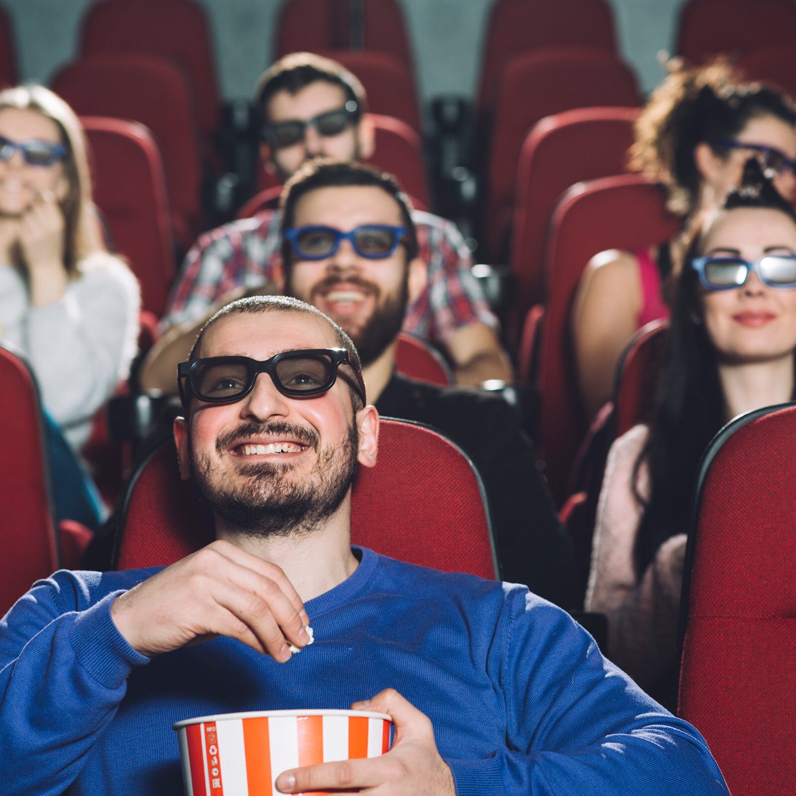 Zdjęcie przedstawia uśmiechniętą grupę osób, siedzących w kinie w okularach trzy de. 