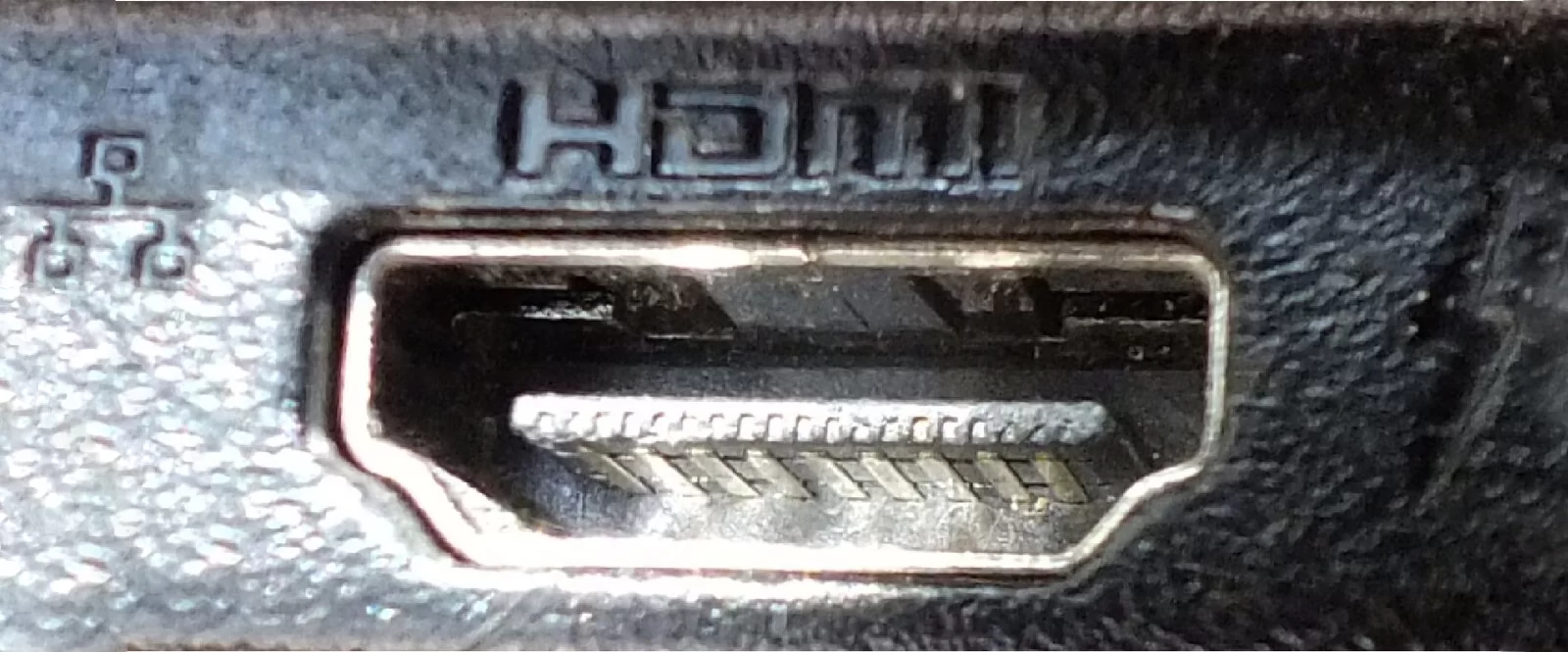 Fotografia przedstawiająca gniazdo HDMI2 - czarny odwrócony trapez z zaokrąglonymi kątami.