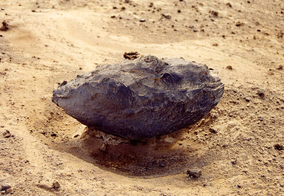 Na zdjęciu bomba wulkaniczna – rodzaj materiału piroklastycznego, który jest wyrzucany w powietrze w czasie wybuchu wulkanu. Jest to kamień o płaskim, półokrągłym kształcie leżący na piasku. 