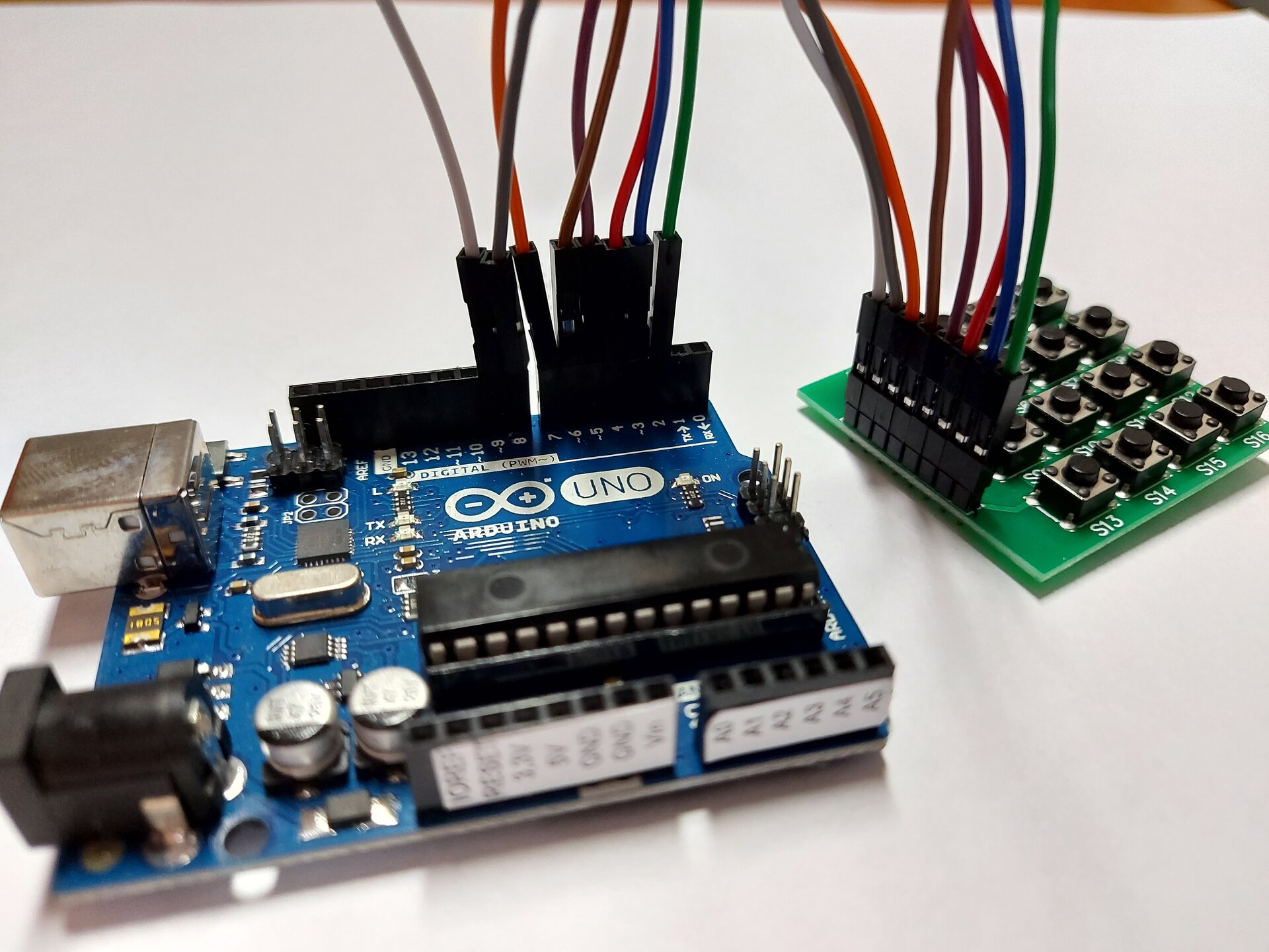 Zdjęcie przedstawia arduino uno połączone kablami do płytki z przyciskami.