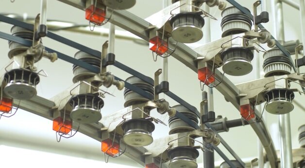 Zdjęcie przedstawia zbliżenie na kształtki. To okrągłe elementy urządzenia umieszczone na metalowych prowadnicach. 