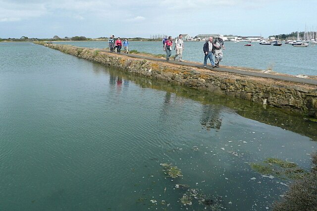 Zdjęcie przedstawia groblę oddzielającą dwa zbiorniki wodne. Na grobli widać ludzi.