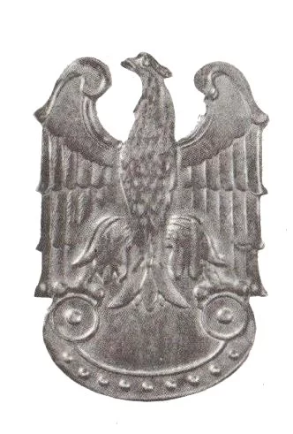 Kliknij, aby powiększyć Zdjęcie przedstawia blaszane godło z orłem. Patrzy w lewo i ma tabliczkę w szponach.