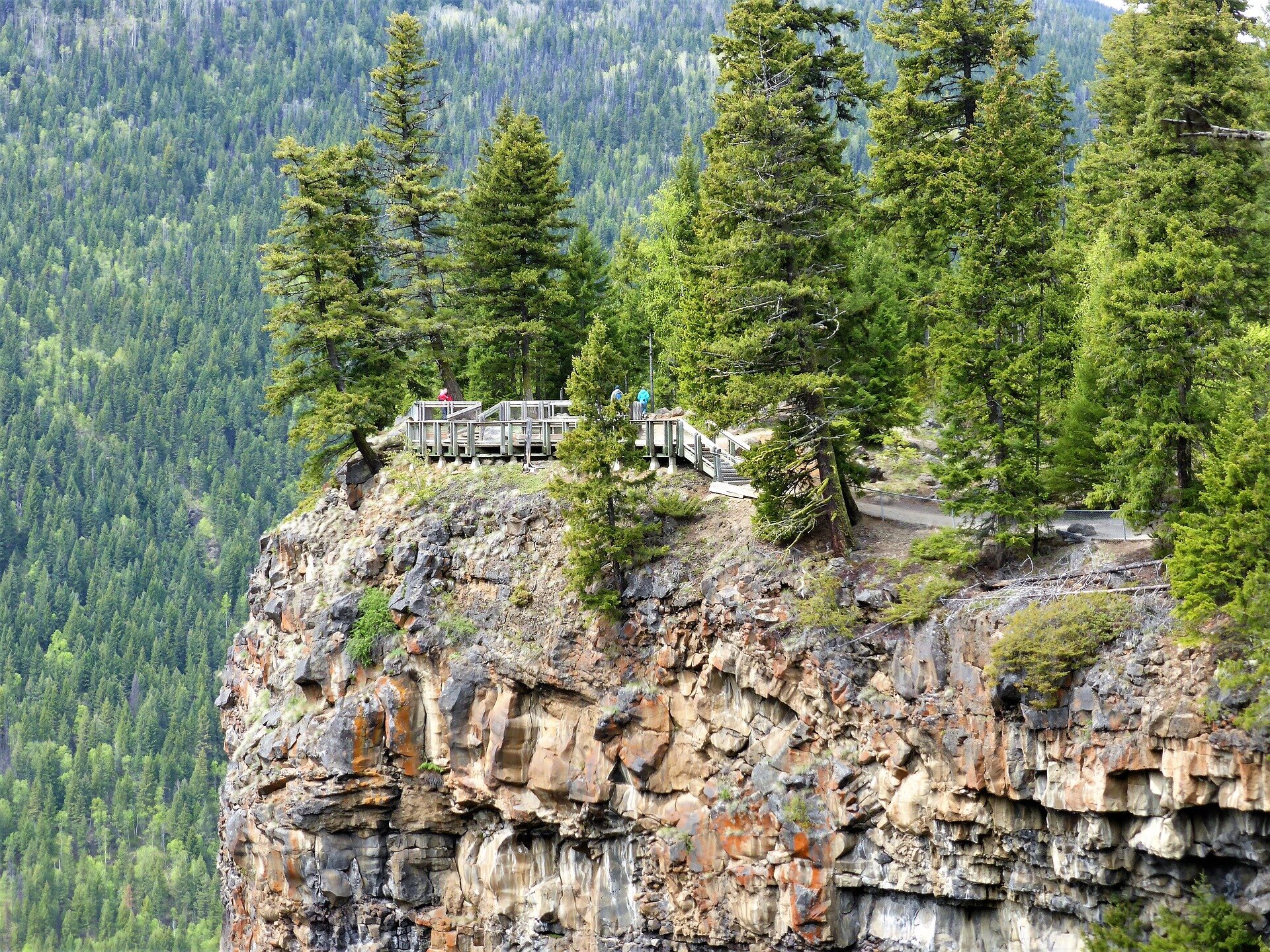 Wysoka skała o nieregularnej budowie. Na jej płaskim szczycie zbudowano taras widokowy z barierkami, stoi na nim kilka osób. Dookoła rośnie kilkanaście drzew iglastych, w dole, poniżej pionowej krawędzi skały, rozpościera się gęsty las.