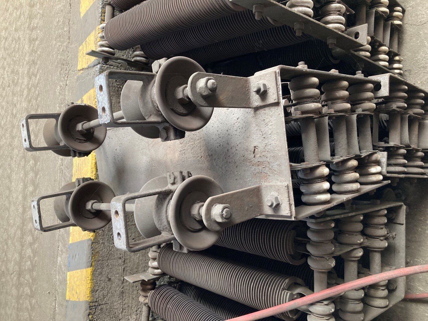 Na zdjęciu widać pięć niepodłączonych sekcji rezystorów rozruchowych. Tylko jedna jest widoczna w całości. Na pierwszym planie widać wyraźnie górną część jej ramy, na której znajdują się cztery izolatory drugiego stopnia. Poniżej widać trzy sworznie wraz z izolatorami na nich zamontowanymi. Na sekcjach po obu stronach widać również wsporniki z segmentami rezystorowymi.