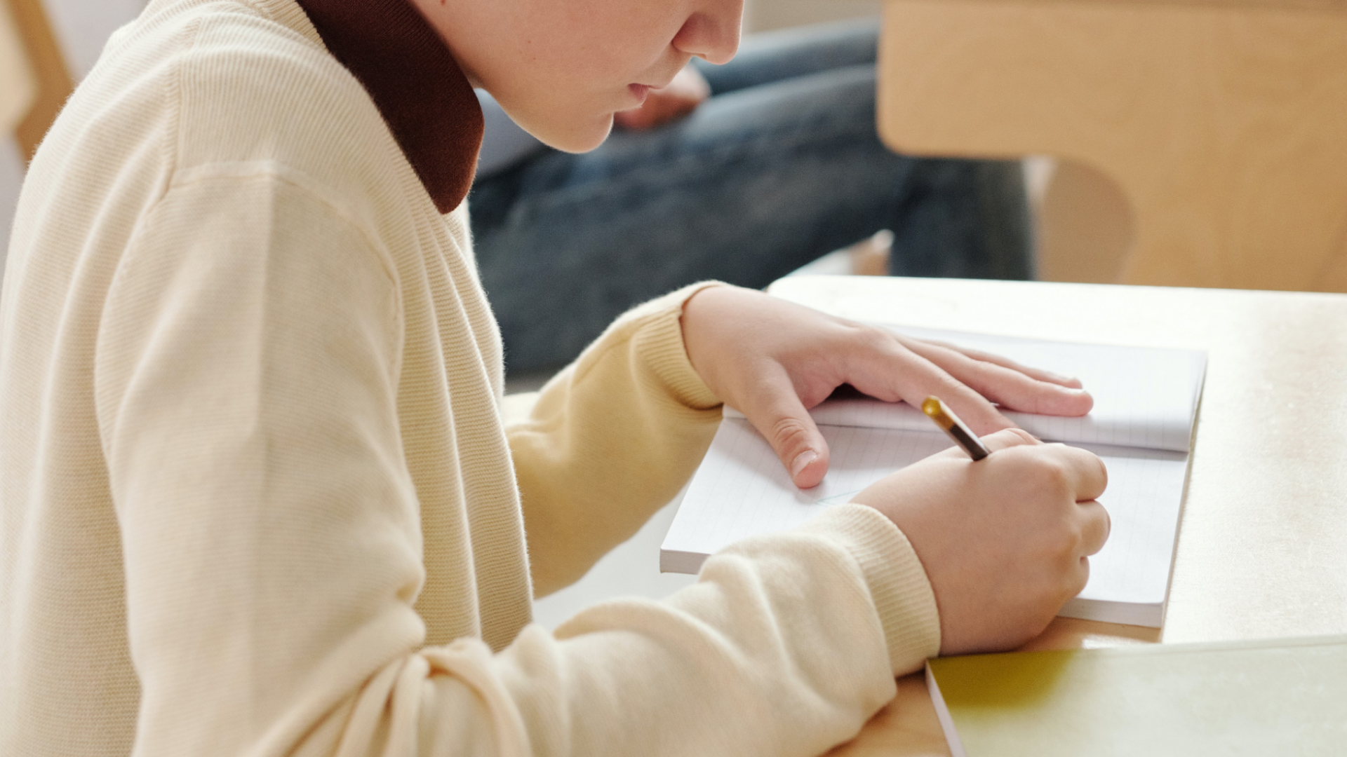 Zdjęcie przedstawia chłopaka robiącego notatki w zeszycie.