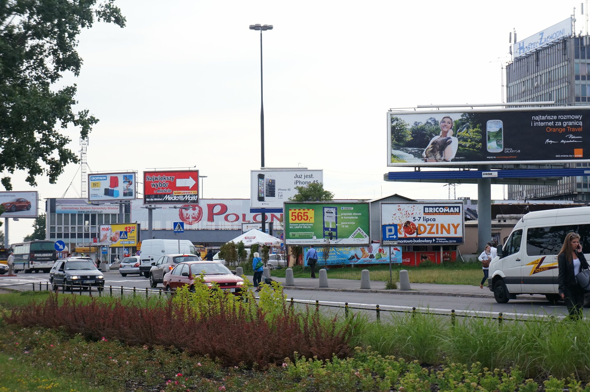 Zdjęcie przedstawia ulicę, wzdłuż której umieszczono kilkanaście tablic i billboardów reklamowych. 