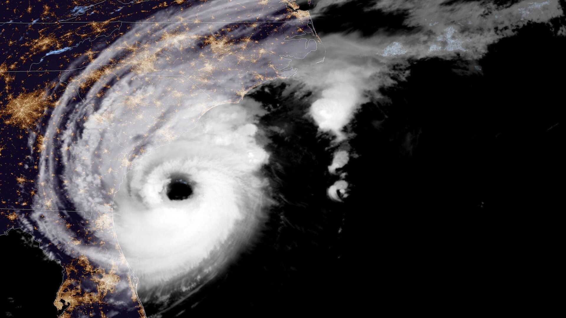 Zdjęcie cyklonu tropikalnego z kosmosu wykonane nocą. Na nim białe chmury burzowe tworzące wir z okiem cyklonu w centralnej części. 