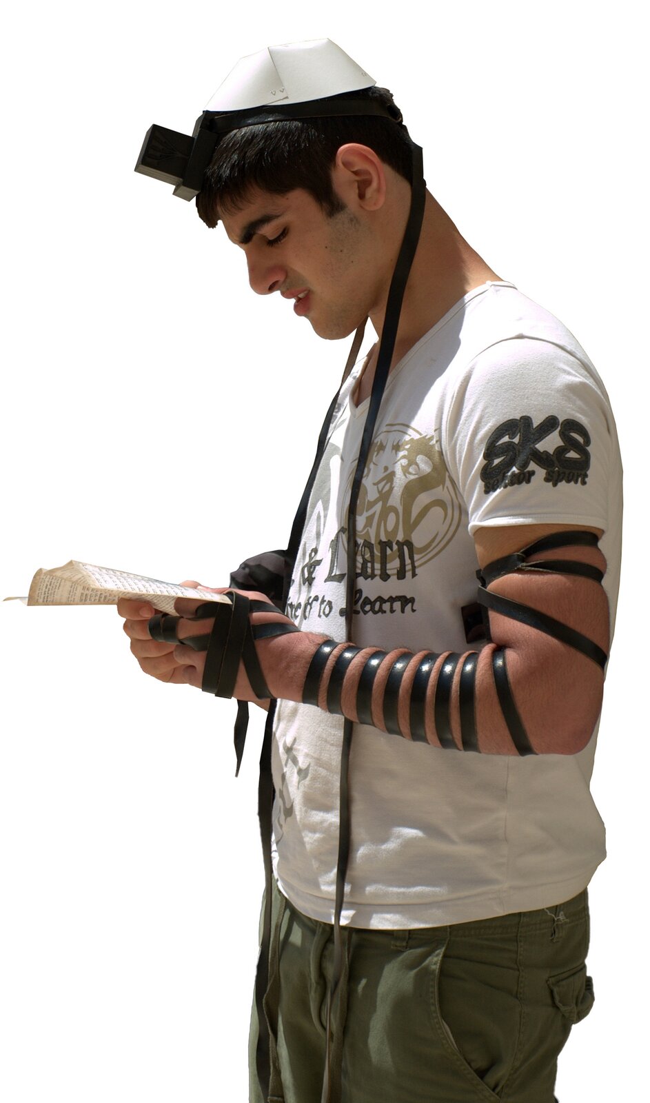 Zdjęcie przedstawia młodego mężczyznę, trzymającego przywiązane do czoła pudełeczko filakterii, a do rąk czarny skórzany pasek, pochylony w modlitwie nad wersetami Tory, stoi zwrócony w stronę lewej krawędzi zdjęcia. Na głowie nosi jarmułkę. Ubrany jest w biały T‑shirt z napisem i spodnie w kolorze khaki.