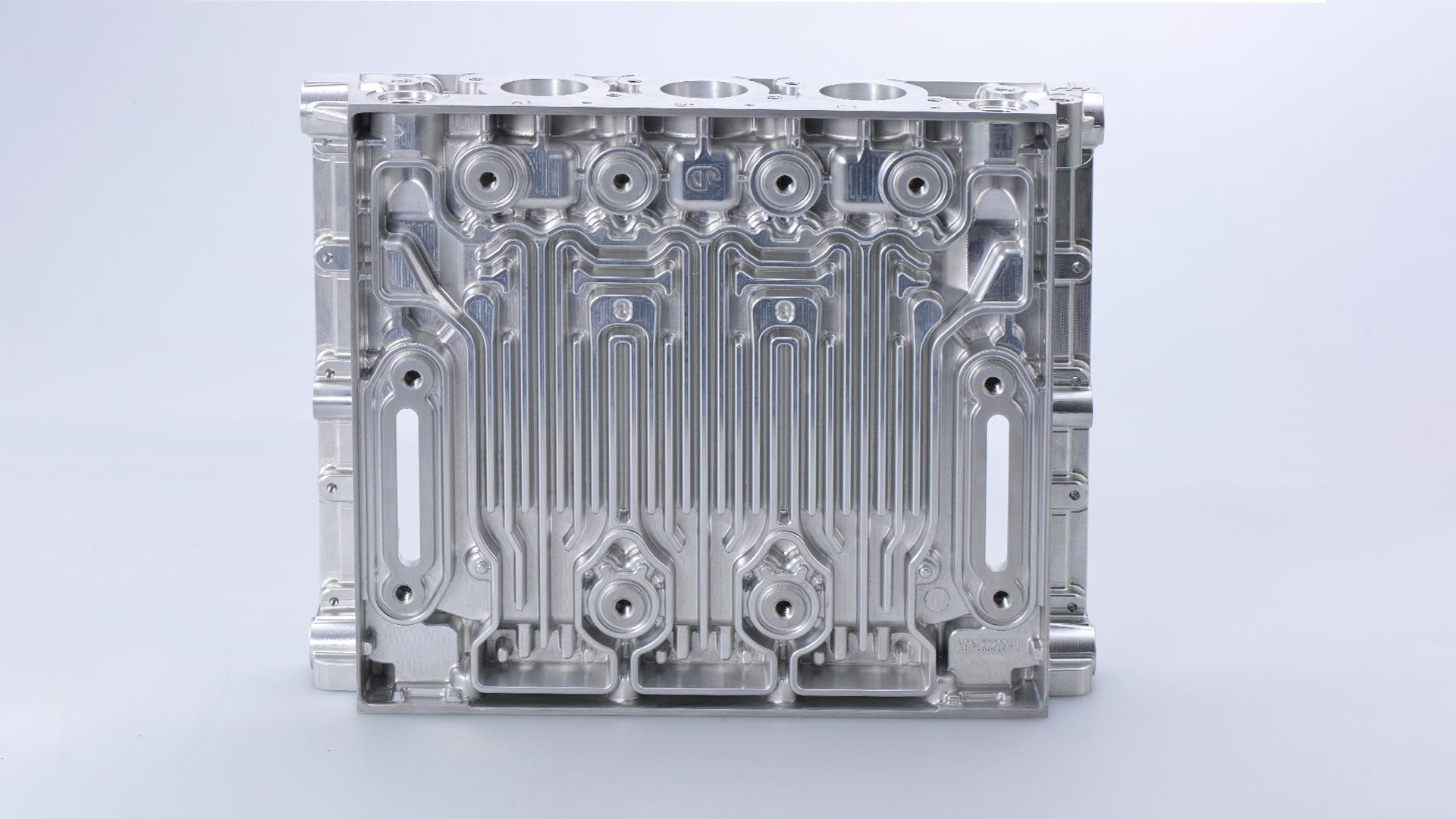 Na grafice znajduje się prostopadłościenny komponent z wytłoczonymi rowkami, otworami, dziurami itp.