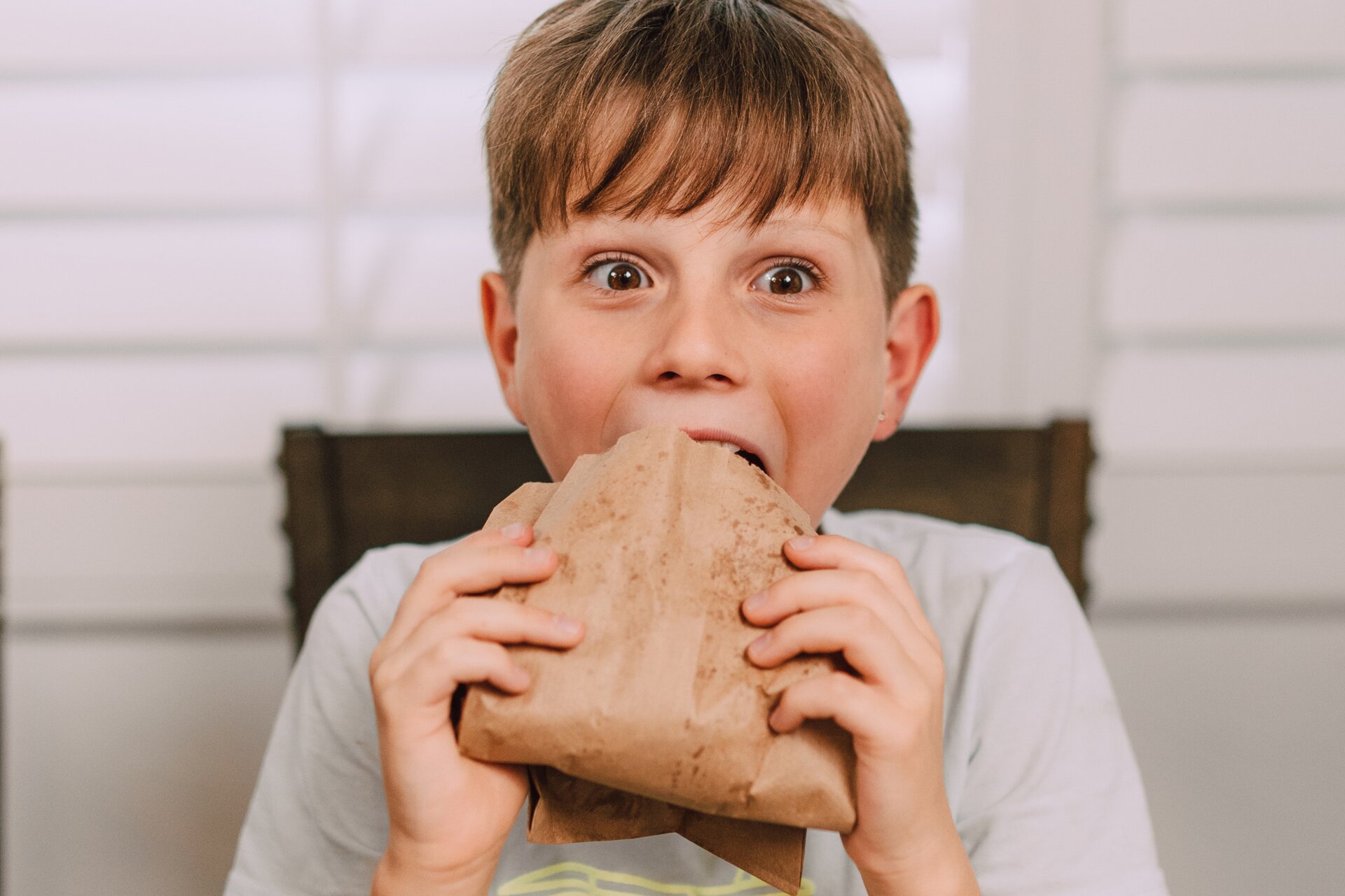 Zdjęcie przedstawia chłopca jedzącego kanapkę.