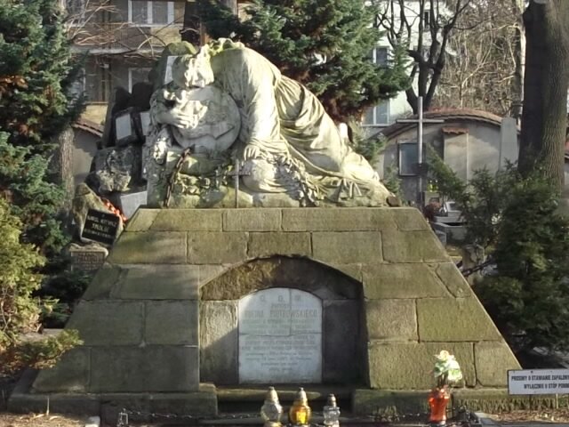 Na zdjęciu znajduje się mogiła Rufina Piotrowskiego na starym cmentarzu w Tarnowie. Grobowiec wykonany z jasnego kamienia. Na nim znajduje się figura Jezusa.
