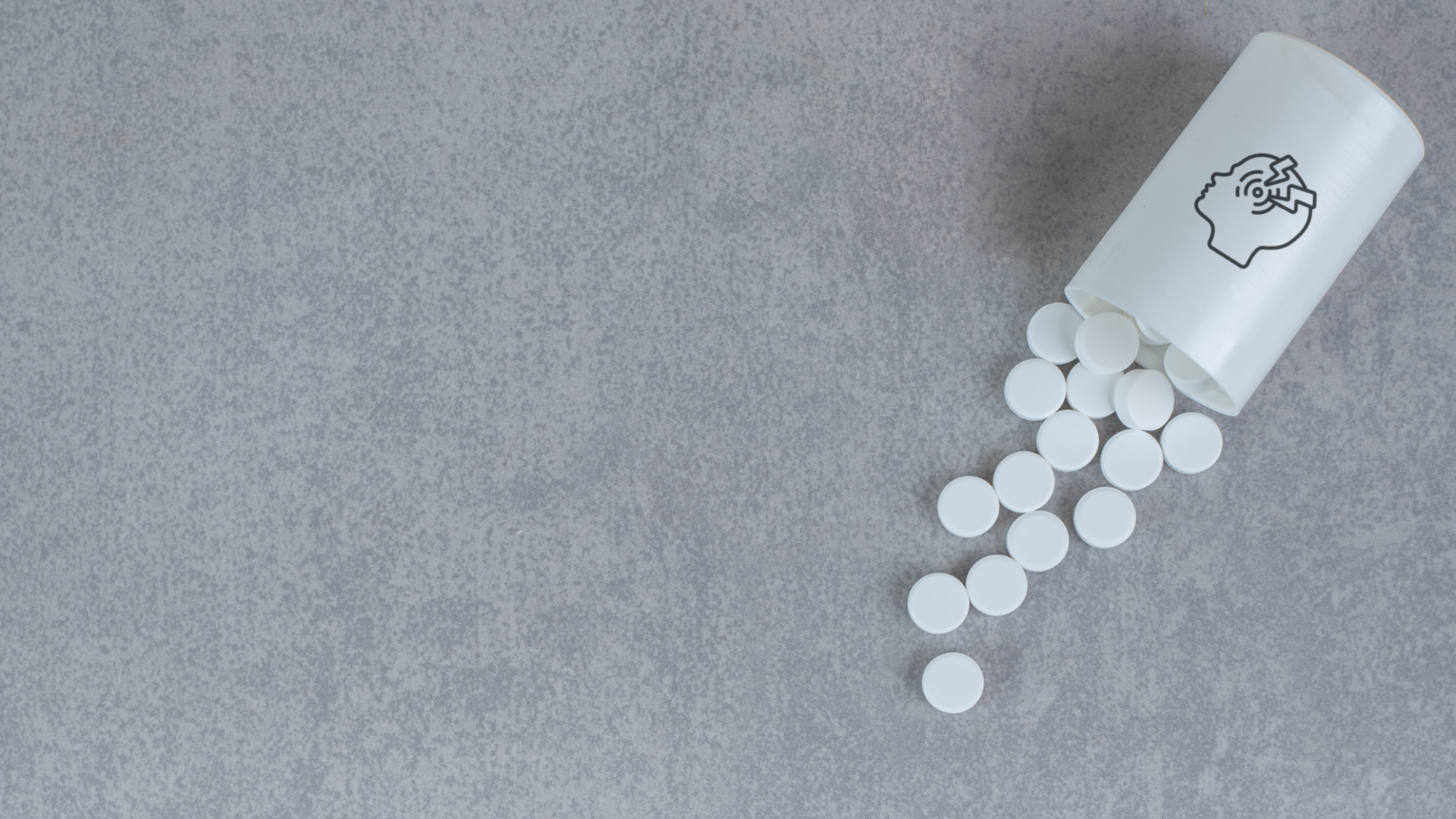 Zdjęcie przedstawia rozsypane tabletki obok plastikowego pojemnika.