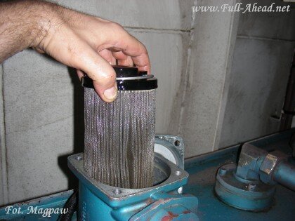 Zdjęcie przedstawia wyjęty filtr oleju. Ma on kształt walca, widać porowatą strukturę.