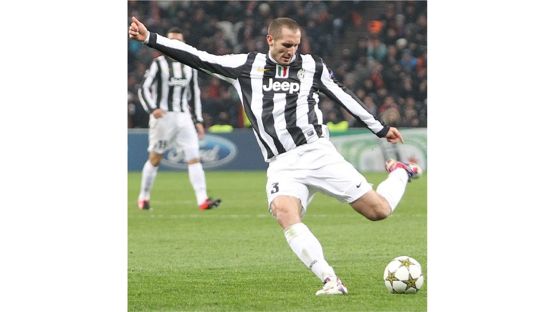 Zdjęcie przedstawia Giorgio Chielliniego w stroju klubowym na boisku. Piłkarz zamierza kopnąć piłkę.