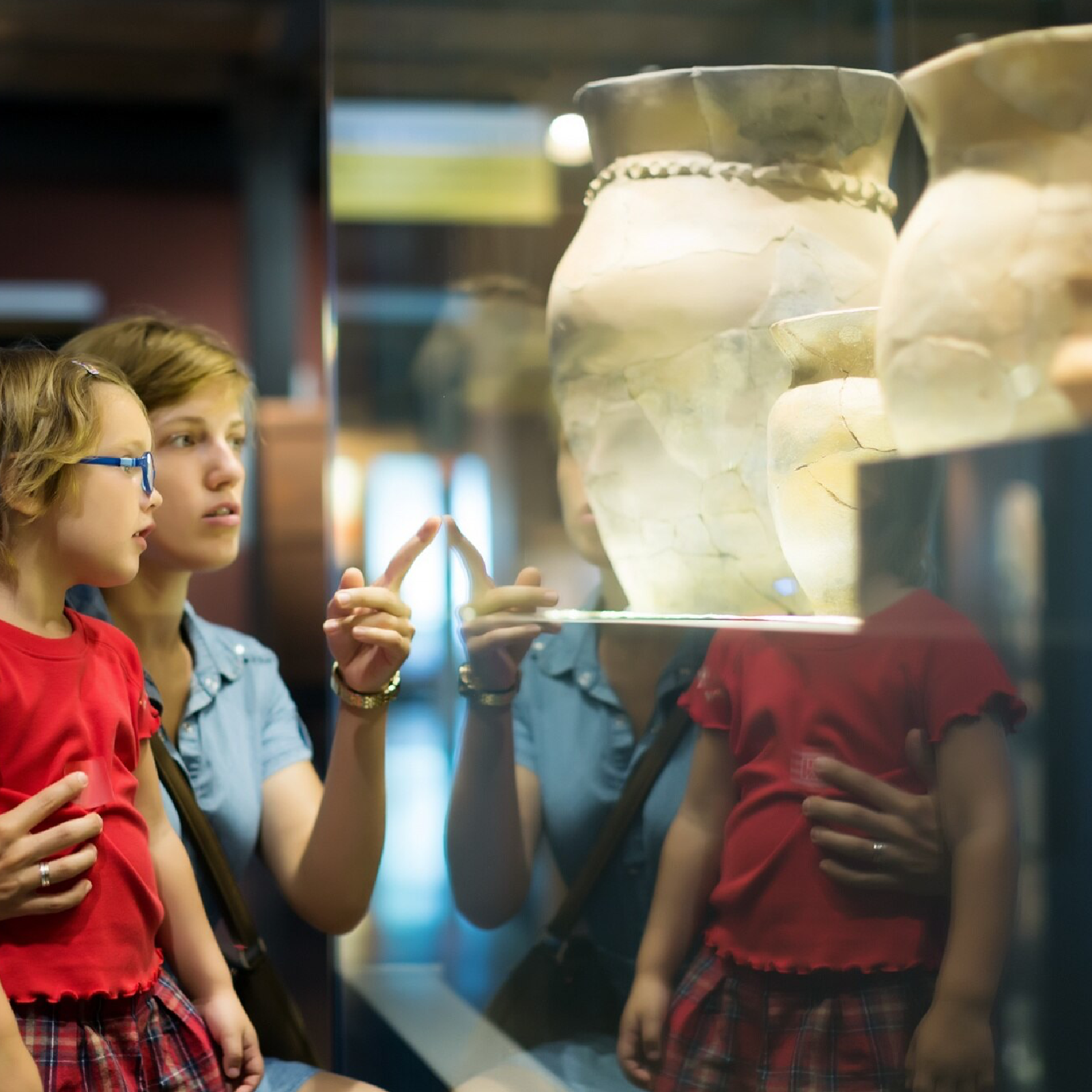 Zdjęcie przedstawia dziewczynkę i chłopca oglądających waze w museum. 