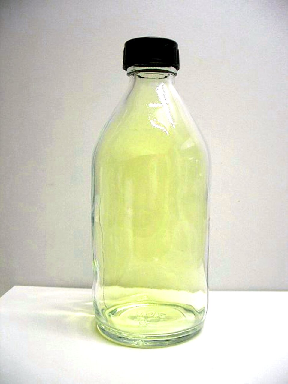 Zdjęcie przedstawia szczelnie zakorkowaną szklaną butlę wypełnioną gazem o żółtawej barwie.