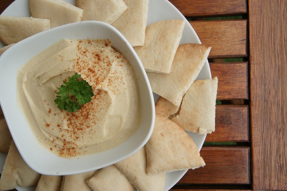 Zdjęcie przedstawia hummus w miseczce. 