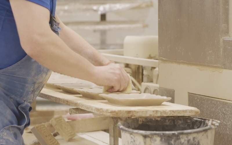 Krok siódmy. Gotowe wyroby ceramiczne. Ósme zdjęcie przedstawia mężczyznę wycierającego gotowe wyroby.