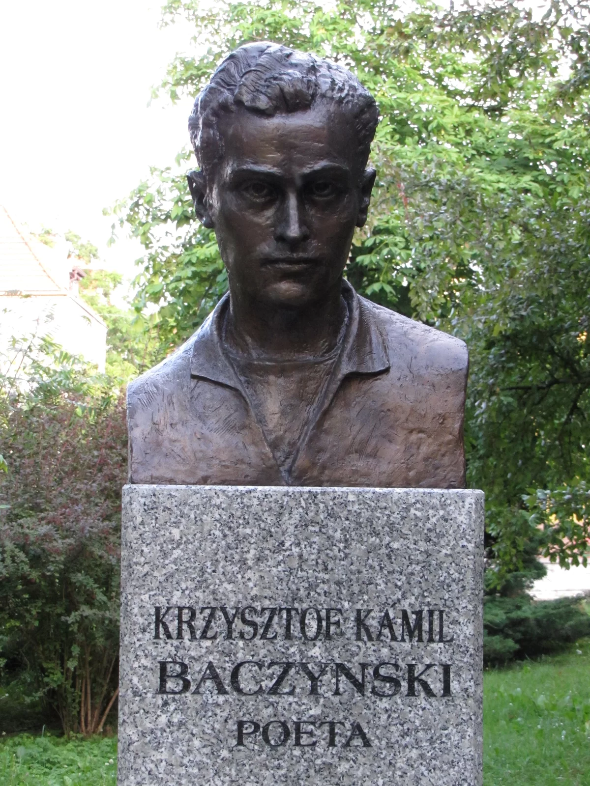 Zdjęcie przedstawia pomnik. Jest to odlana z mosiądzu rzeźba popiersia poety. Jest on przedstawiony jako młody człowiek. Na postumencie widnieje napis: Krzysztof Kamil Baczyński poeta.