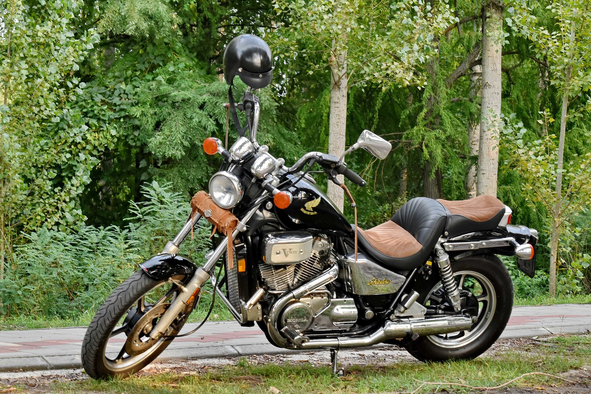 Zdjęcie przedstawia hondę. Motocykl jest smukły, długi. Przednia opona jest cieńsza od tylnej. Motocykl ma miękkie, komfortowe siedzenia - dla kierowcy i pasażera. Widoczne chromowane, odsłonięte części motocykla.  