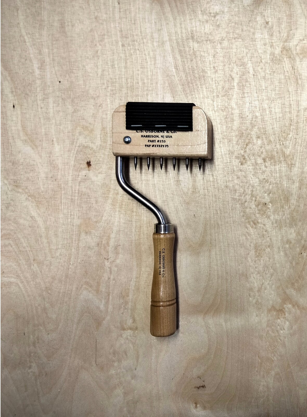 Na zdjęciu przedstawiono pasociąg. Przyrząd posiada drewnianą główkę z metalowymi kolcami, która osadzona jest na metalowym trzonku zakończonym drewnianym uchwytem.