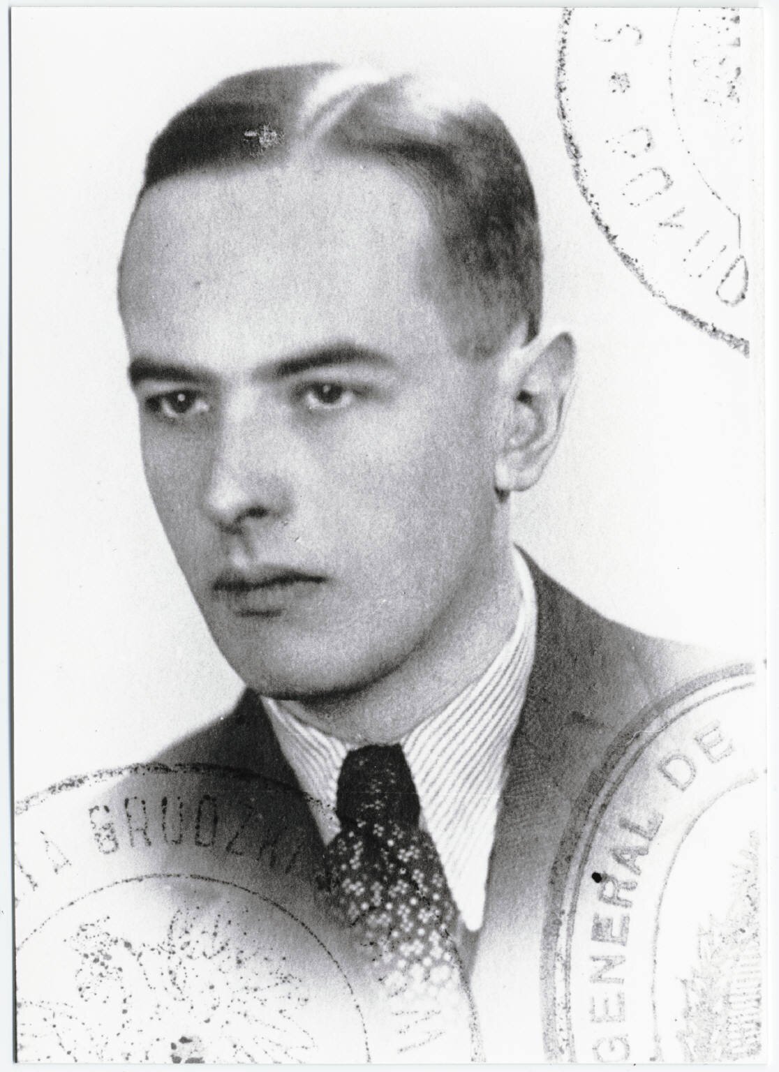 Czarno-białe zdjęcie paszportowe Witolda Gombrowicza z  1939 roku. Ma on krótkie włosy zaczesane na lewą stronę. Jest ubrany w koszulę z zawiązanym krawatem i marynarkę. Spogląda w stronę widza. Ma odsłonięte prawe ucho. Postać została przedstawiona do wysokości barków.  W dolnych rogach są widoczne fragmenty pieczątek. W górnym prawym rogu widnieje część stempla. Mężczyznę otacza jasne tło. Zdjęcie ma kształt prostokąta.