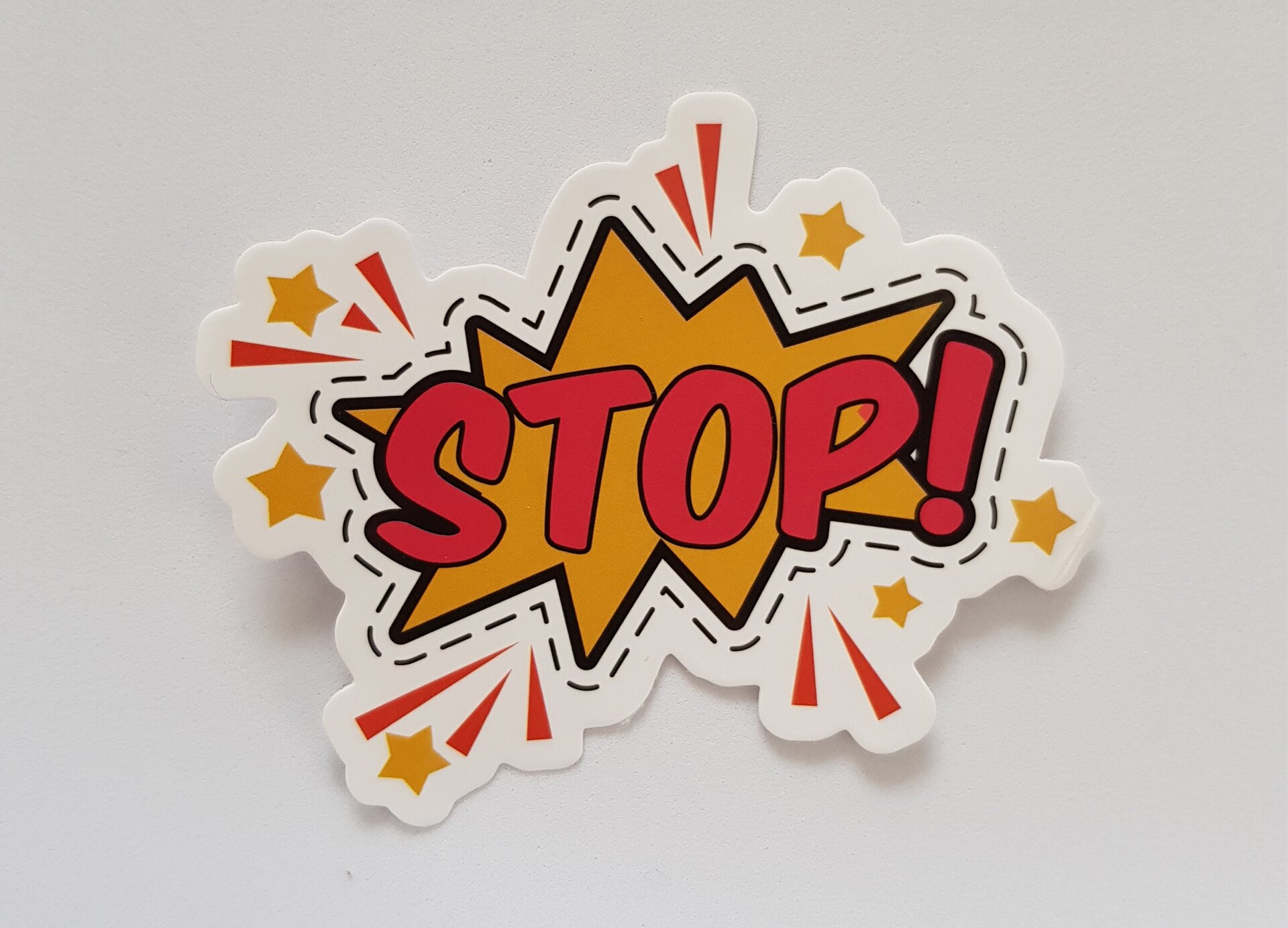 Zdjęcie przedstawia wielokształtny znaczek, w środku którego widoczna jest zniekształcona żółta gwiazda, otoczona promykami i gwiazdkami, z wpisanym dużym czerwonym napisem STOP z wykrzyknikiem.