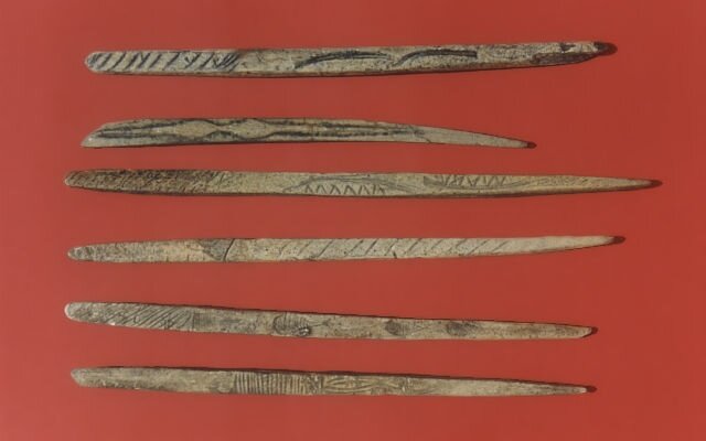 Ilustracja przedstawia wyroby z kości. Mają postać podłużnych szpikulców. Z jednej strony są zakończone obłym kształtem, z drugiej szpiczastym. Na ich powierzchni znajdują się wyryte wzory.