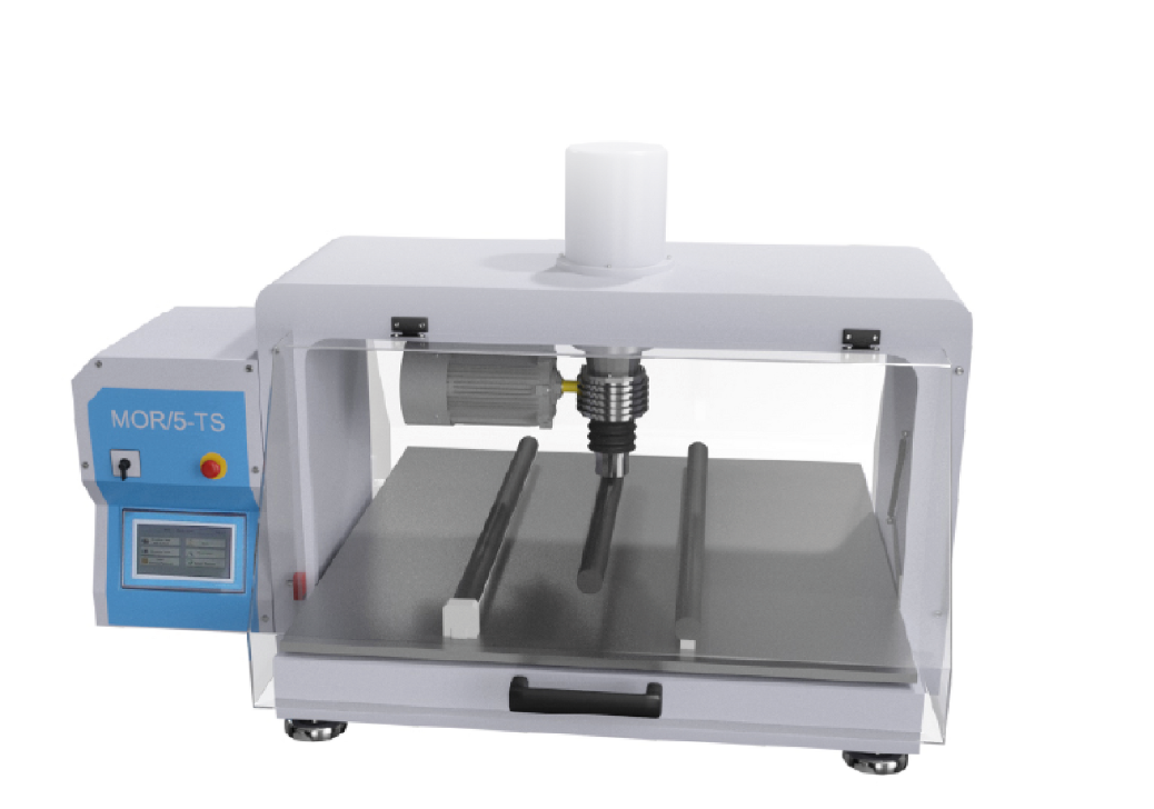 Ilustracja przedstawia urządzenie. To łamacz. Jest to maszyna o kształcie sześcianu z przeszklonym frontem. Wewnątrz jej znajduje się ramię, do którego przymocowana jest czarna rurka. Po jej lewej stronie znajduje się niebieski panel z napisem: MOR/5‑TS. Na panelu tym znajduje się również pokrętło, czerwony przycisk oraz mały ekran.