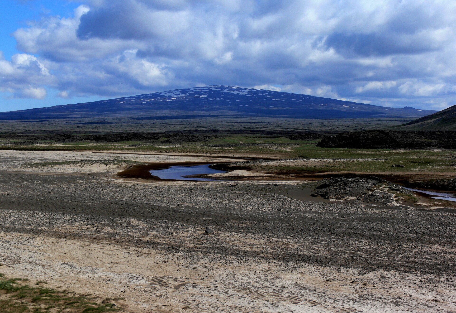 Tytuł zdjęcia to Skjaldbreiður, National Park of Þingvellir, Iceland. Fotografia przedstawia wygasły wulkan tarczowy Skjaldbreiður, który ostatni raz wybuchł ponad 7500 lat temu. Ten niewysoki, spłaszczony wulkan położony jest w południowo-zachodniej Islandii.