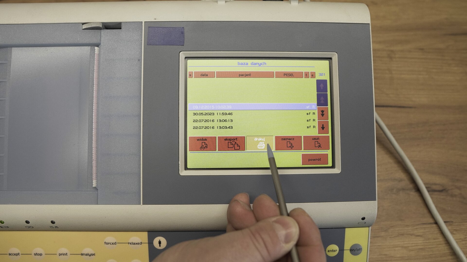 Na zdjęciu technik wybiera na klawiaturze ekranowej spirometru  przycisk Drukuj.