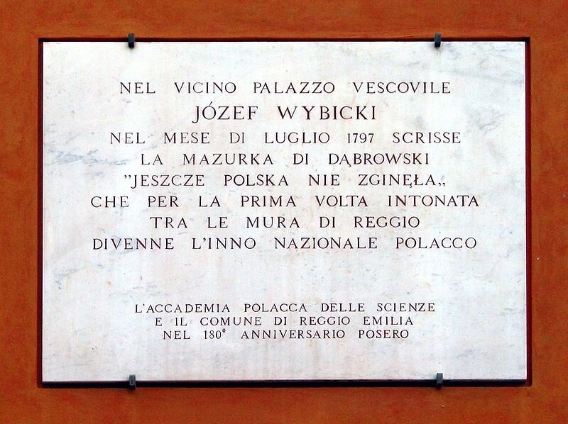 Na zdjęciu znajduje się tablica z brązową ramą. Na białym tle widnieje napis w języku francuskim, upamiętniający napisanie hymnu narodowego przez Józefa Wybickiego. Na dole zostało zapisane miejsce i data.