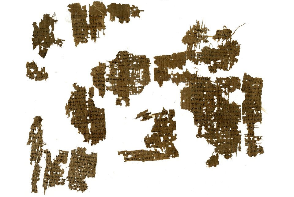 Na ilustracji znajdują się fragmenty strony Septuaginty. Są zapisane ręcznie czarnym tuszem lub atramentem na pożółkłym papirusie. Kawałki papirusu są ułożone na białym tle, mają różną wielkość.