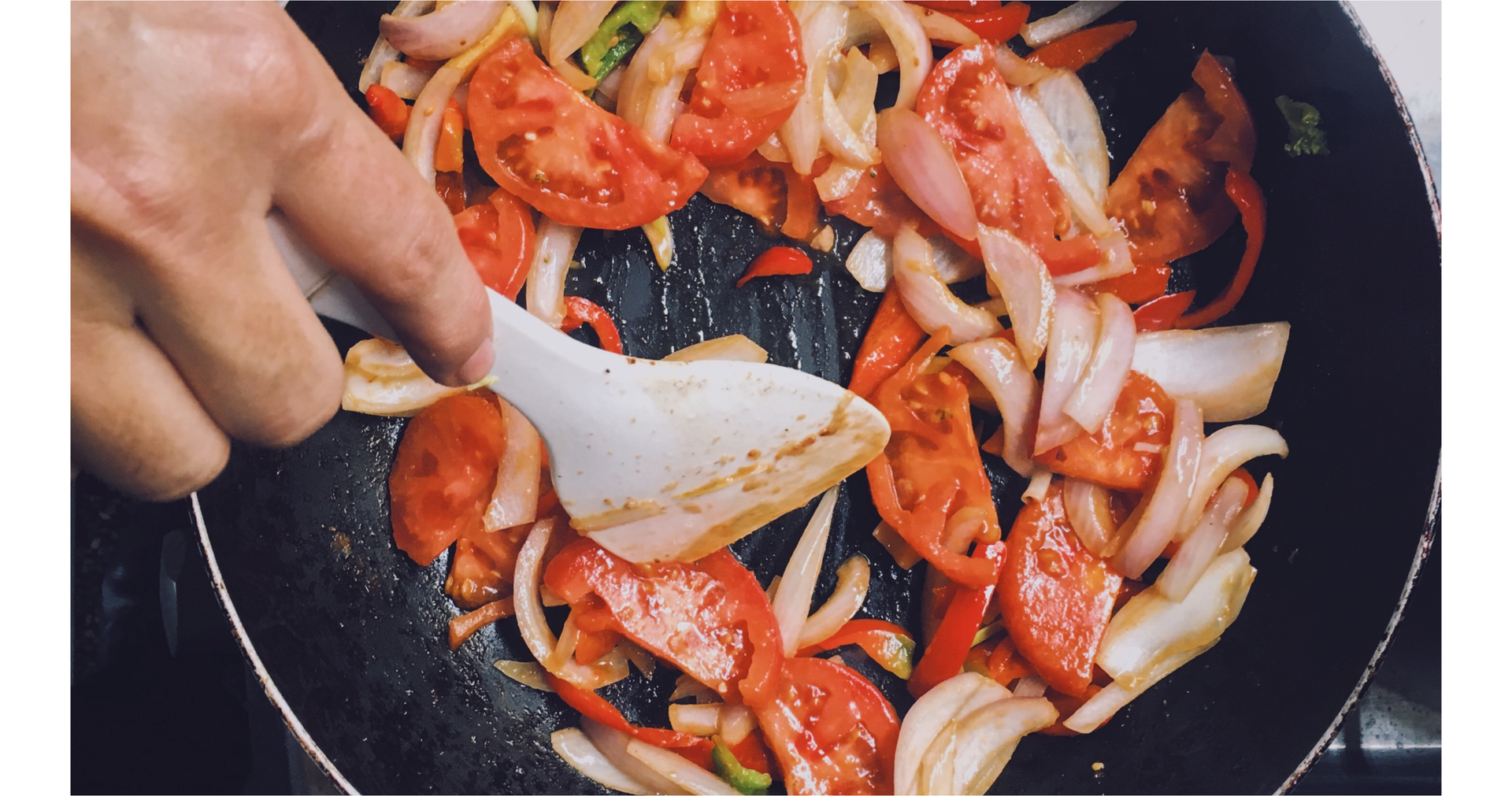 Zdjęcie przedstawia rękę osoby, która miesza produkty smażące się na patelni.