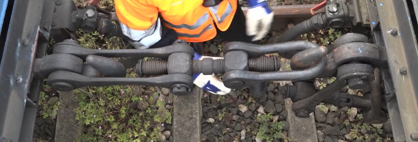 Zdjęcie przedstawia sprzęg śrubowy. Widoczny na zdjęciu sprzęg jest zahaczony z prawej strony o hak wagonu i przytwierdzony na stałe z lewej strony do drugiego wagonu. Pomiędzy hakami znajduje się dwustronna śruba ściągająca wagony do siebie.