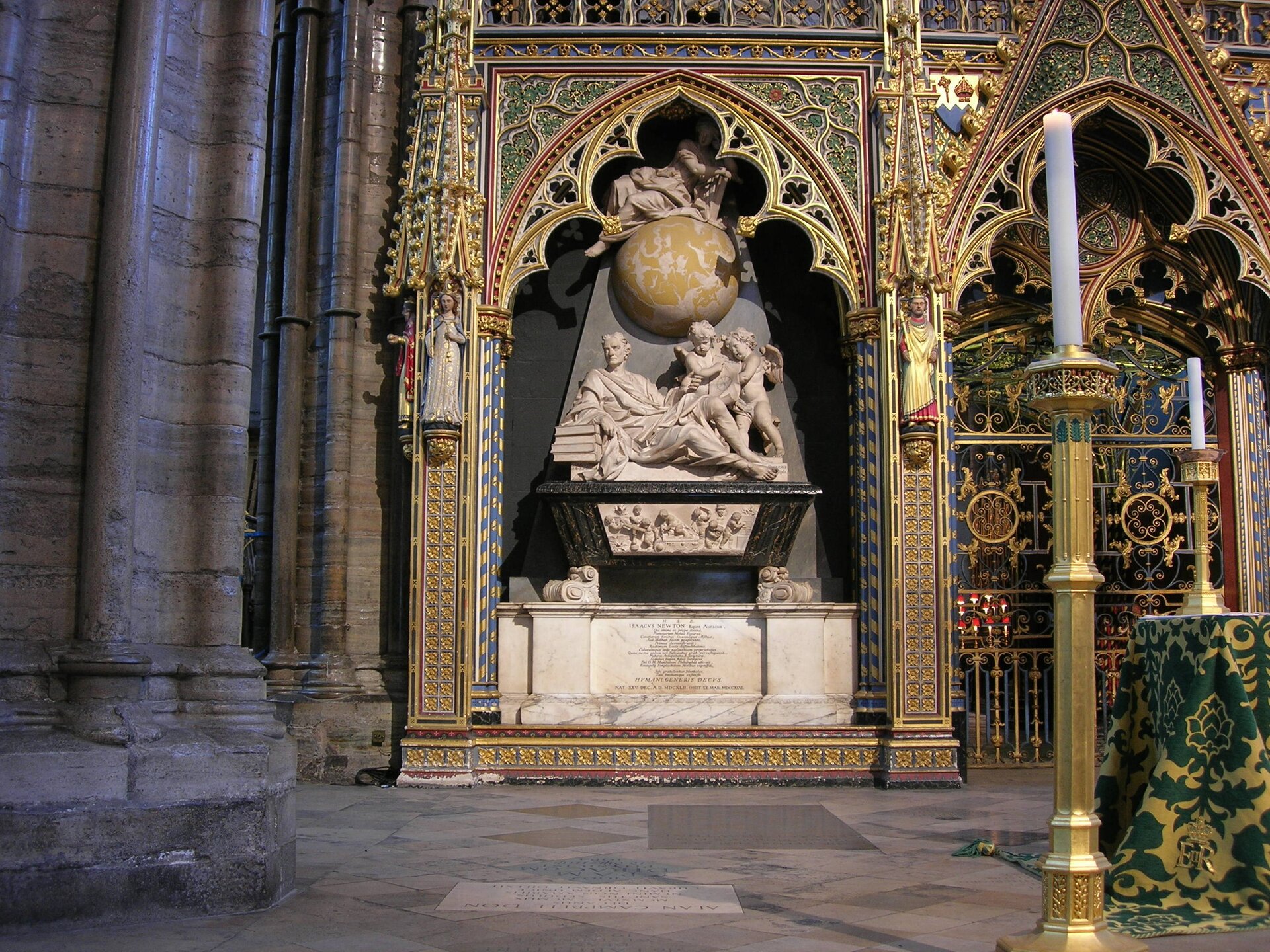 Zdjęcie bardzo bogatego, zdobionego, nagrobka położonego we wnęce w ścianie świątyni. Po bokach złote kolumny. Na nagrobku znajdują się rzeźby nad nimi kula, na niej kolejna rzeźba w pozycji pół leżącej. 