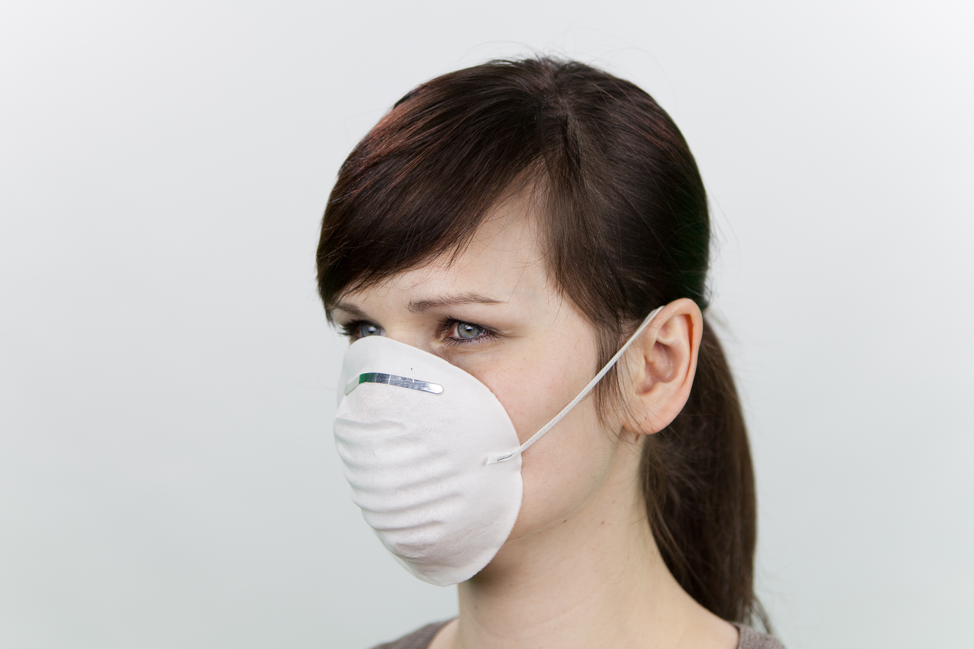 Fotografia przedstawia młodą kobietę w maseczce ochronnej na twarzy. Maseczka zakrywa jej nos i usta.