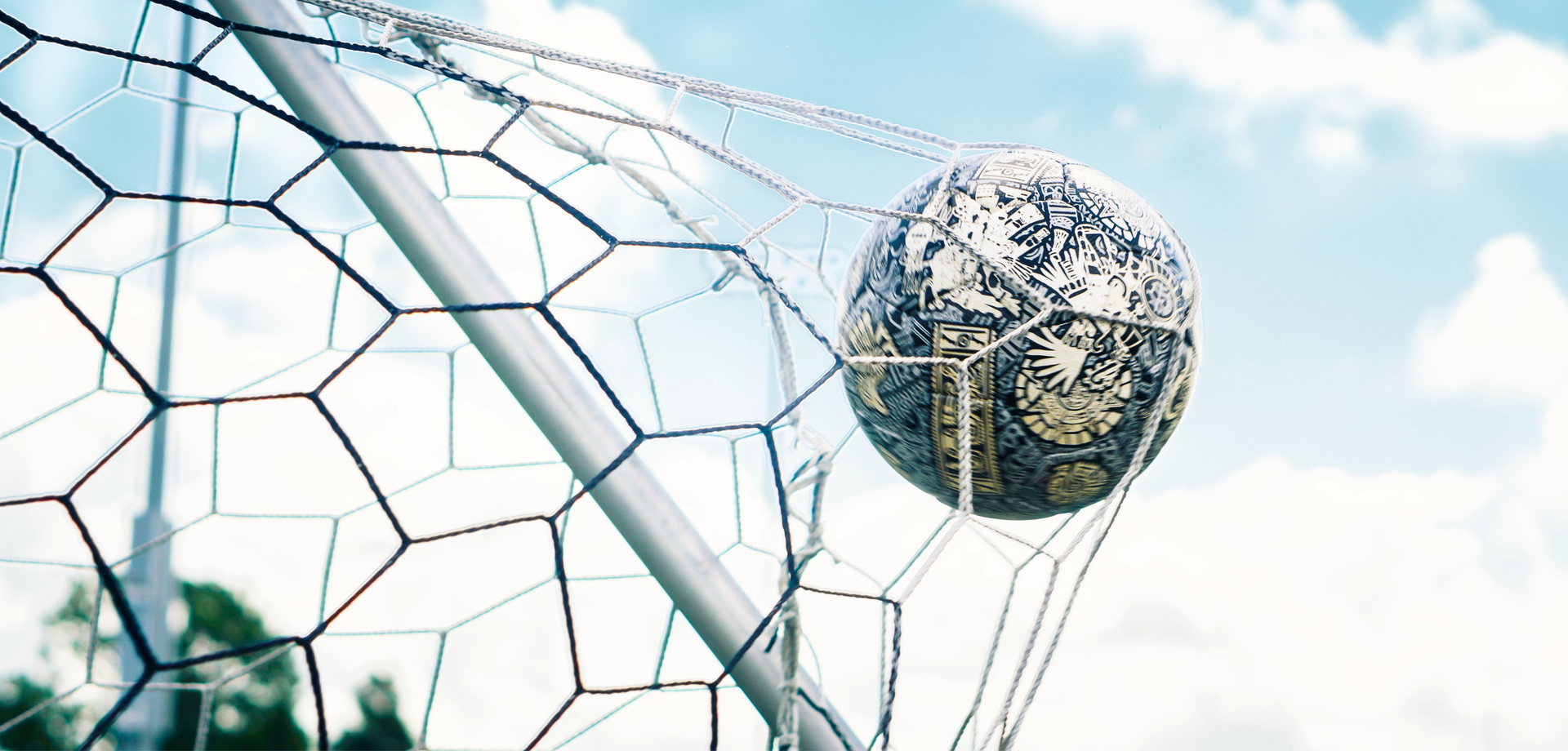 Zdjęcie przedstawia zbliżenie na piłkę do gry w piłkę nożną. Piłka wpada do siatki w bramce. Siatka rozciąga się od siły z jaką piłka wpada do siatki.