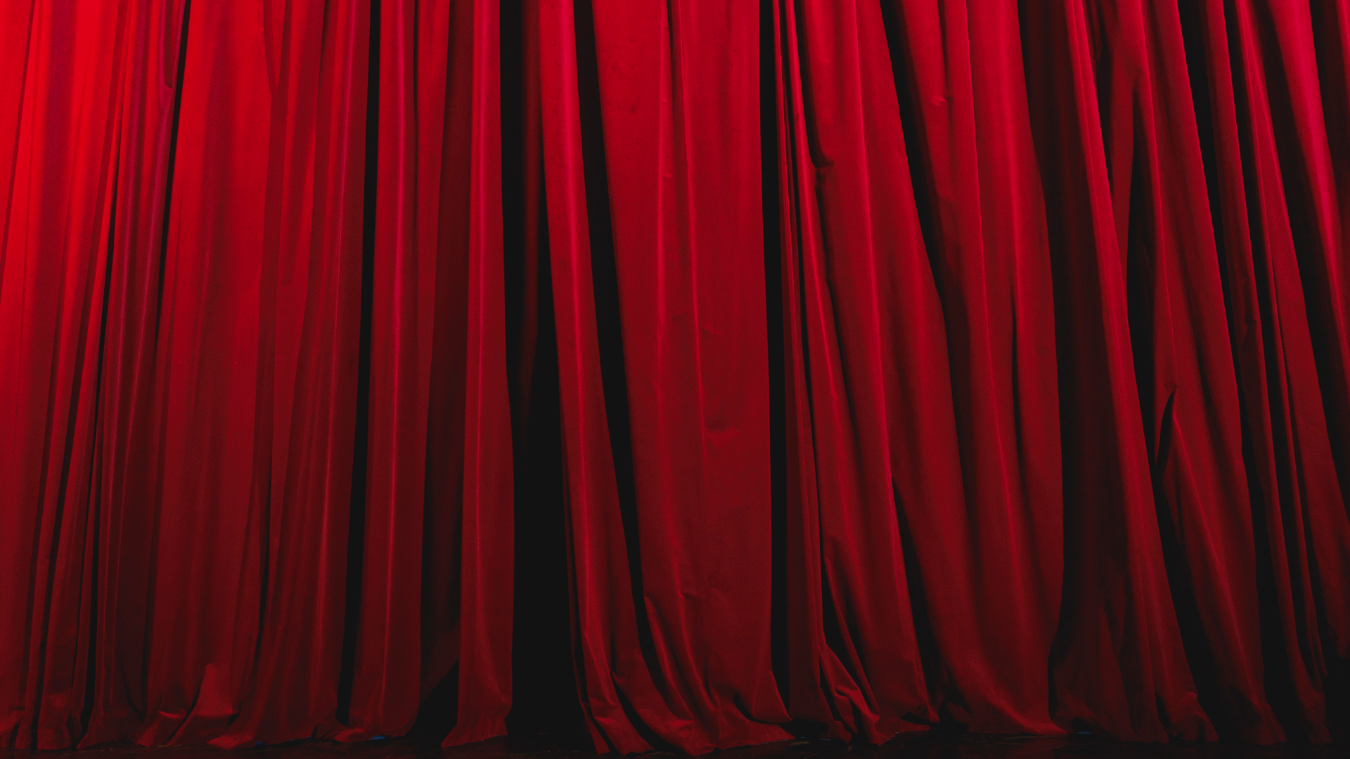 Zdjęcie przedstawia gęsto umarszczoną, ciężką, welurową kurtynę teatralną. Kurtyna jest rozsunięta, zasłania scenę. 