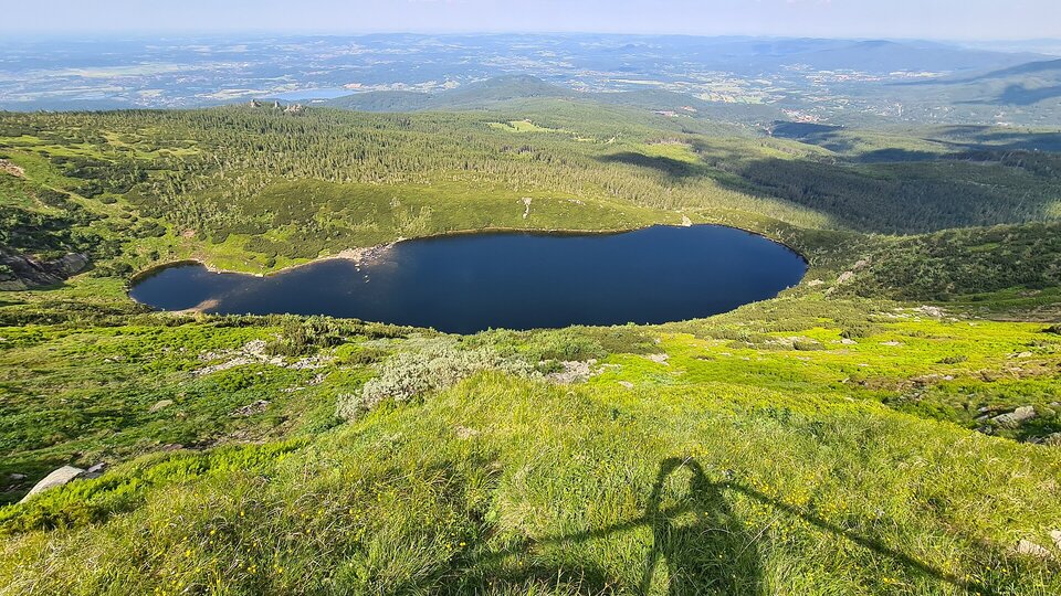 Na fotografii widać Kocioł Wielkiego Stawu w Karkonoszach. Jest to zagłębienie otoczone zboczami górskimi. W zagłębieniu znajduje się jezioro – Wielki Staw. Zbocza górskie są pokryte głównie trawami i licznymi pojedynczymi skałami.