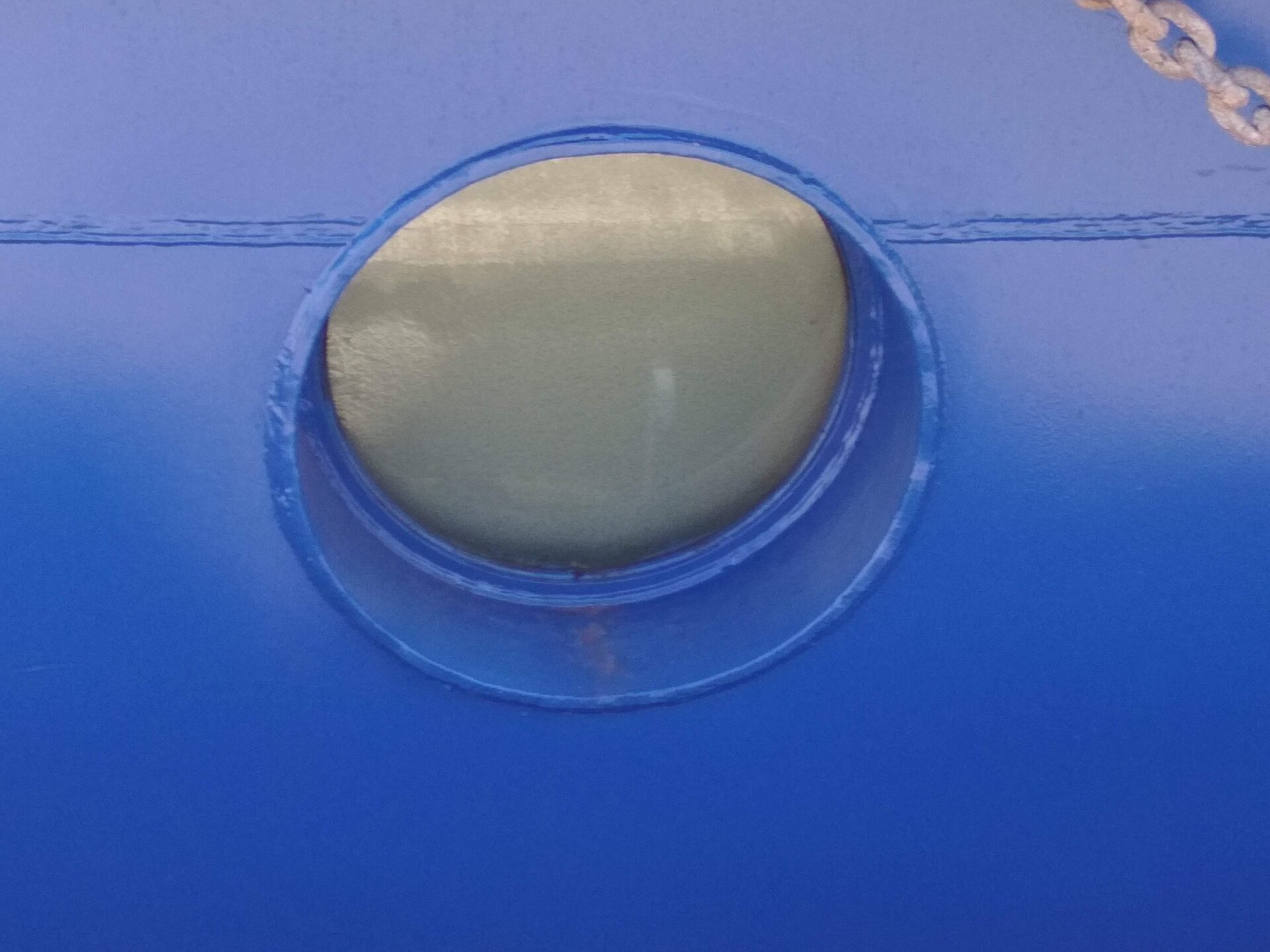 Zdjęcie przedstawia iluminator. Jest to okrągły otwór w poszyciu kadłuba.