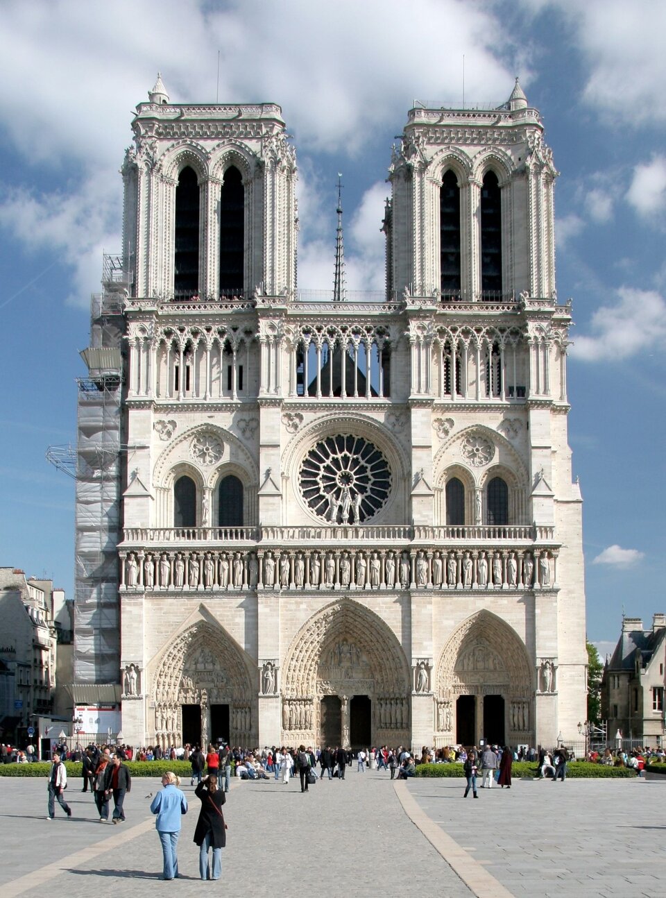 Zdjęcie przedstawia front katedry Notre Dame. Po bokach dwie masywne wieże płaskie u góry, bez strzelistych zakończeń. Centralne miejsce fasady zajmuje rozeta. Do budowy katedry użyto jasnego kamienia. Do katedry prowadzą trzy bramy — wejścia.