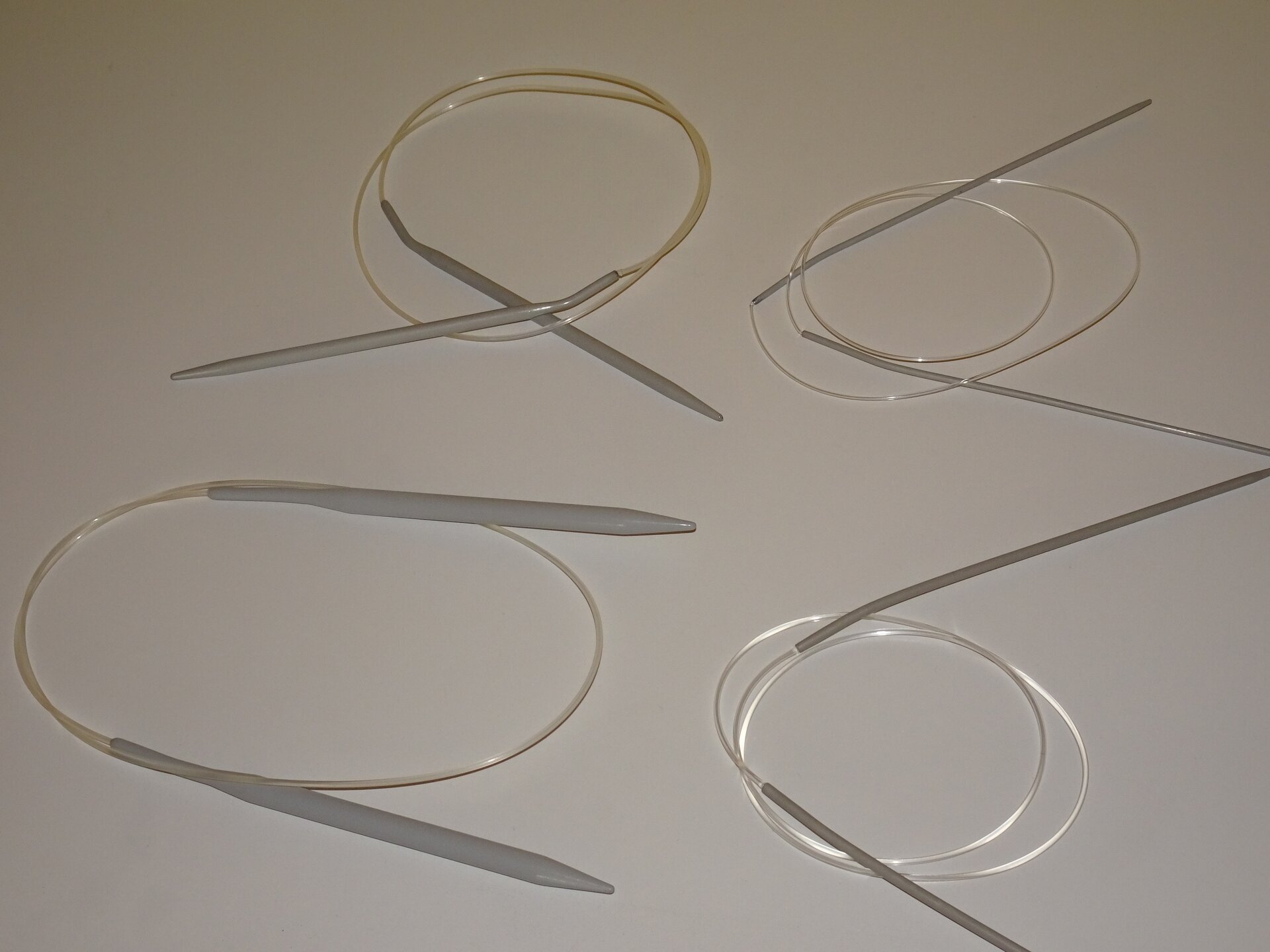 Zdjęcie przedstawia cztery pary drutów służących do ręcznego wytwarzania dzianin. Każda para metalowych drutów połączona jest żyłką z tworzywa sztucznego. Pary drutów są różnej grubości.